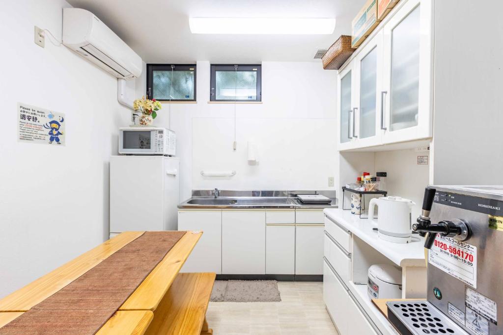 une cuisine avec des armoires blanches et une table en bois dans l'établissement add-Hostel Uji Cha-gan-ju-tei, à Uji