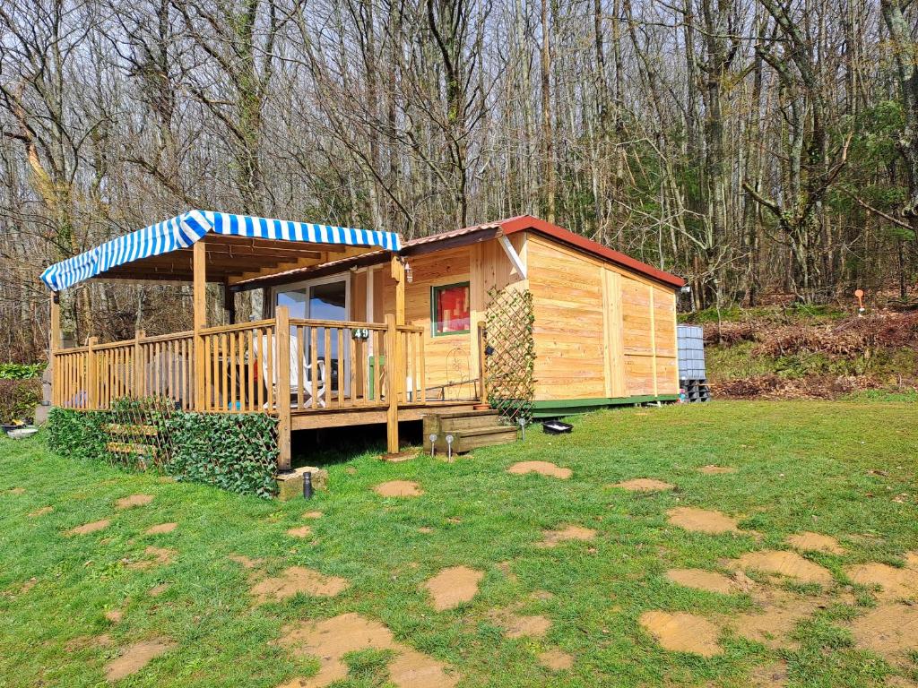 une cabane en bois avec une terrasse dans une cour dans l'établissement Camping le Bois Jahan, à Brunelles