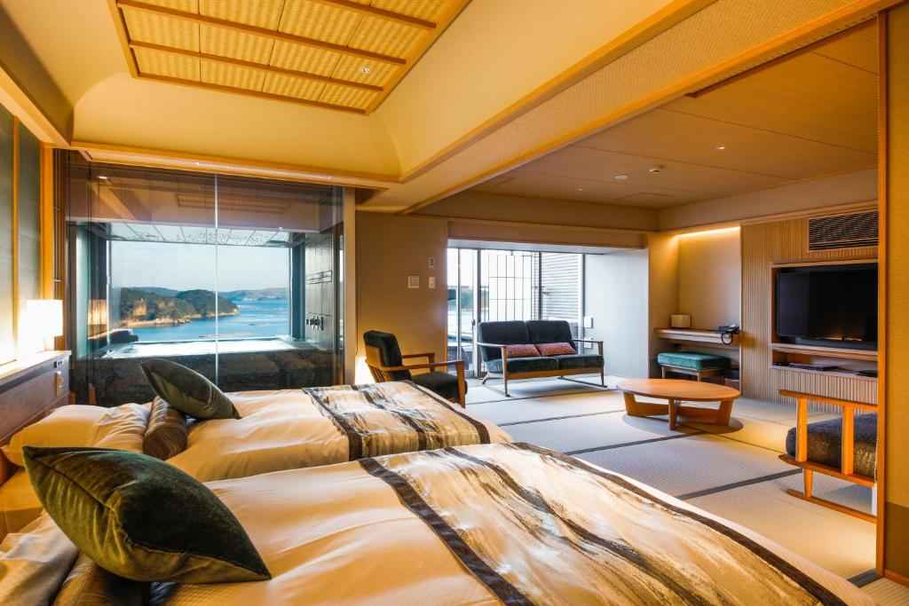 une chambre d'hôtel avec deux lits et une grande fenêtre dans l'établissement Sun Urashima Yuki no Sato, à Toba