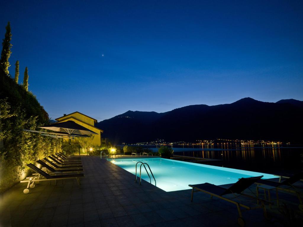 - une piscine de nuit avec des montagnes en arrière-plan dans l'établissement Filario Hotel & Residences, à Lezzeno