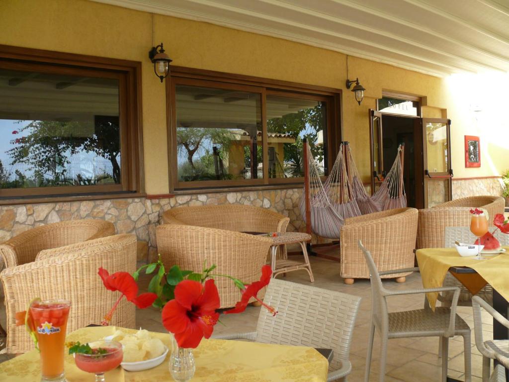 un restaurant avec des tables et des chaises avec des fleurs rouges dessus dans l'établissement Alba D'Amore Hotel & Spa, à Lampedusa