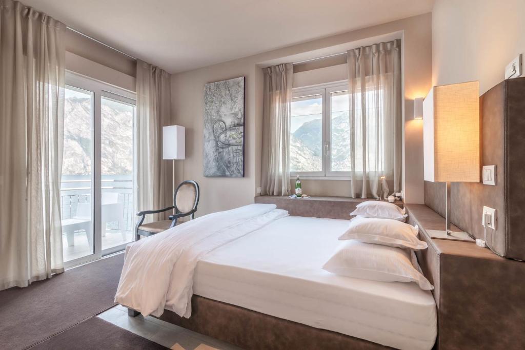 - une chambre avec un grand lit blanc et des fenêtres dans l'établissement Villa Tempesta, à Nago-Torbole