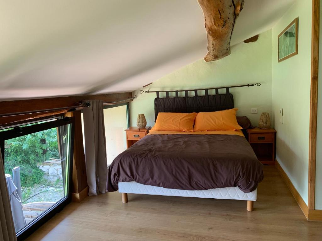 une chambre avec un lit et une grande fenêtre dans l'établissement Gîte Bois et Senteurs, à Lafrançaise