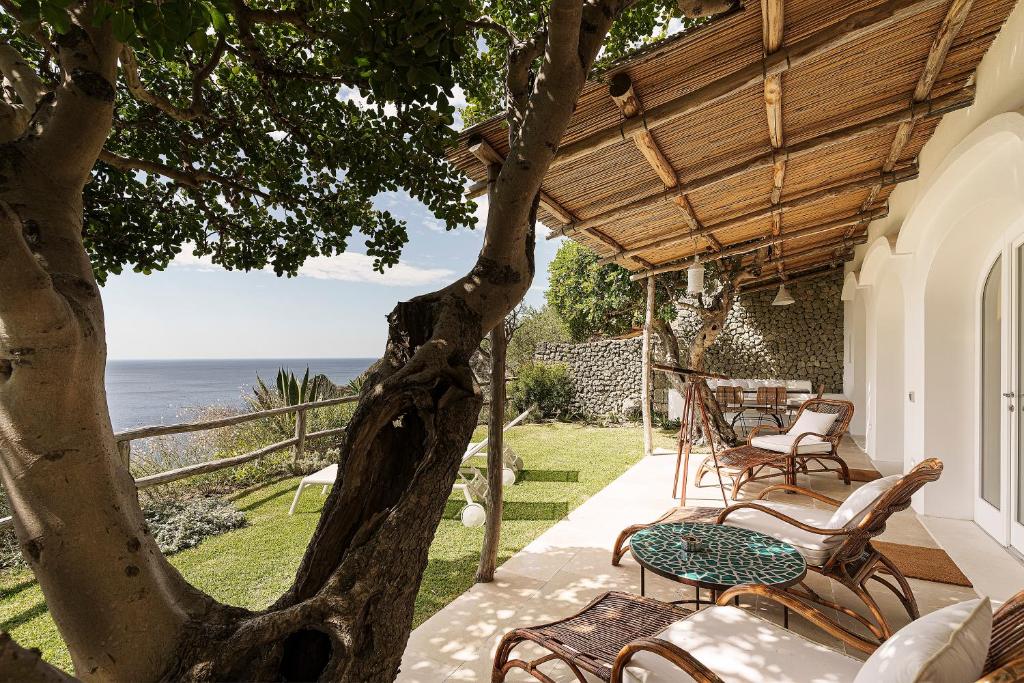 un patio avec des chaises, une table et un arbre dans l'établissement Costa Del Capitano Seaside Villas, à Ischia