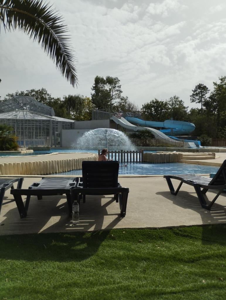 un homme assis sur un banc devant un parc aquatique dans l'établissement MOBIL HOME 4p, à Piriac-sur-Mer