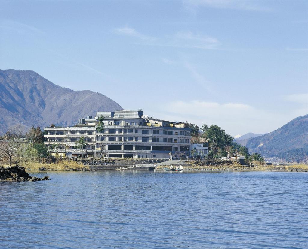 un grand bâtiment blanc sur le côté d'un lac dans l'établissement Maruei, à Fujikawaguchiko