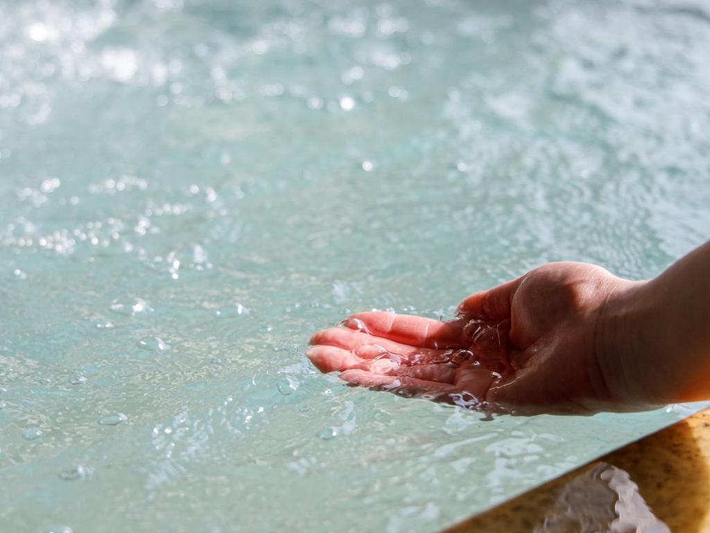 une personne tenant la main dans l'eau dans l'établissement Hotel Iwasuge, à Yamanouchi