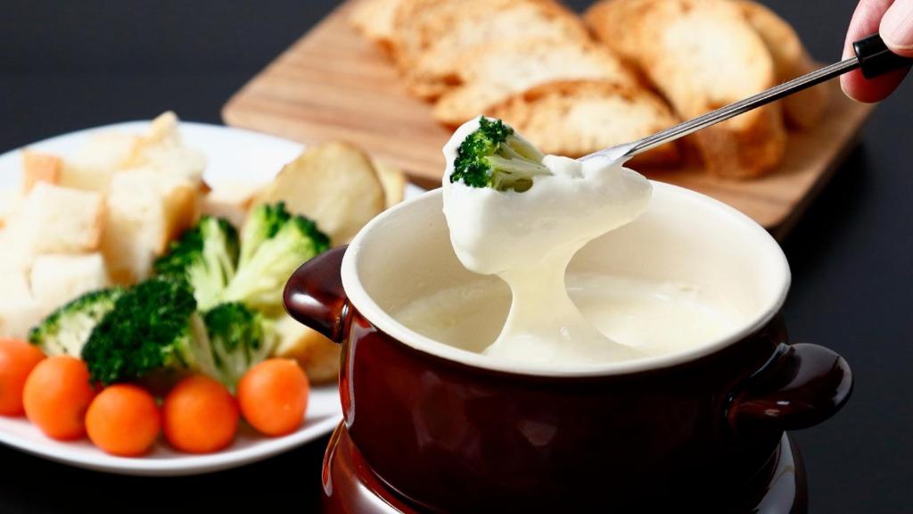 Une personne plongeant du brocoli dans une tasse de yaourt. dans l'établissement Sounkyo Kankou Hotel, à Kamikawa 8 autres photos