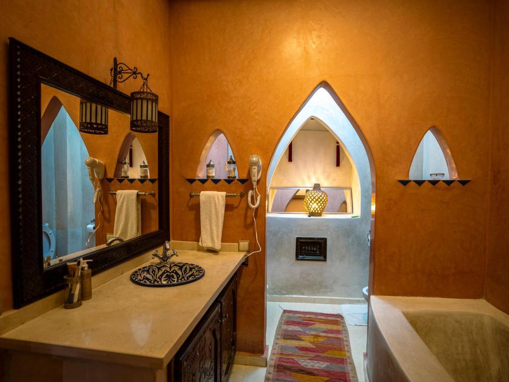 une salle de bain avec un lavabo et un grand miroir dans l'établissement Riad 58 Blu, à Marrakech