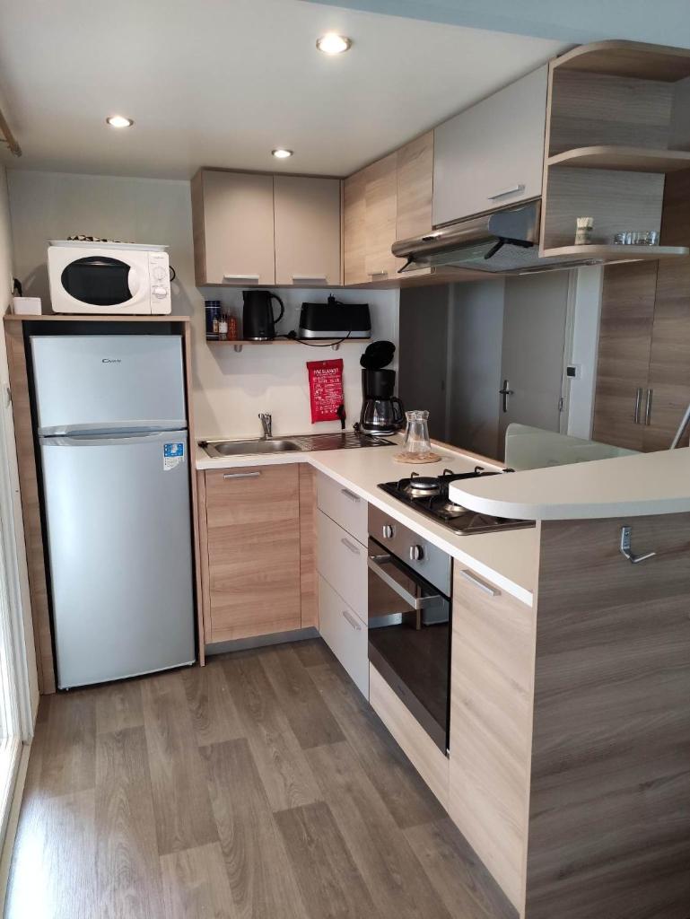 Il comprend une cuisine équipée d'un réfrigérateur et d'une cuisinière. four supérieur dans l'établissement Mobil-home 6/8 personnes au Domaine de Kerlann, Pont-Aven, à Pont-Aven