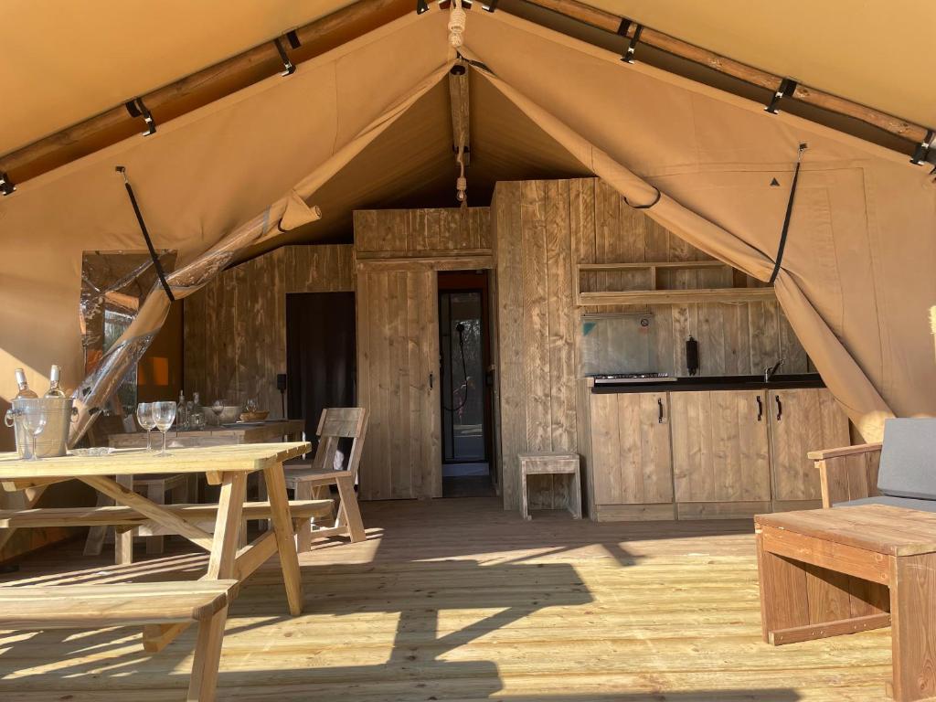 une tente avec une table et des chaises sur du parquet dans l'établissement Lodges & Nature - 49, à Avignon