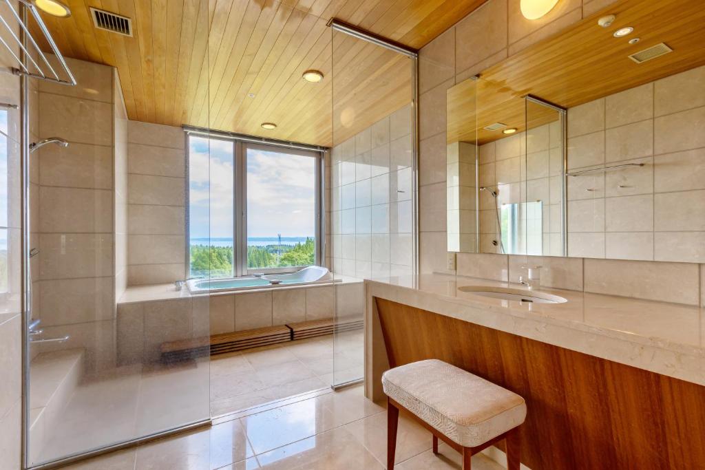 une salle de bain avec une baignoire, un lavabo et un miroir dans l'établissement KAMENOI HOTEL Aomori Makado, à Noheji