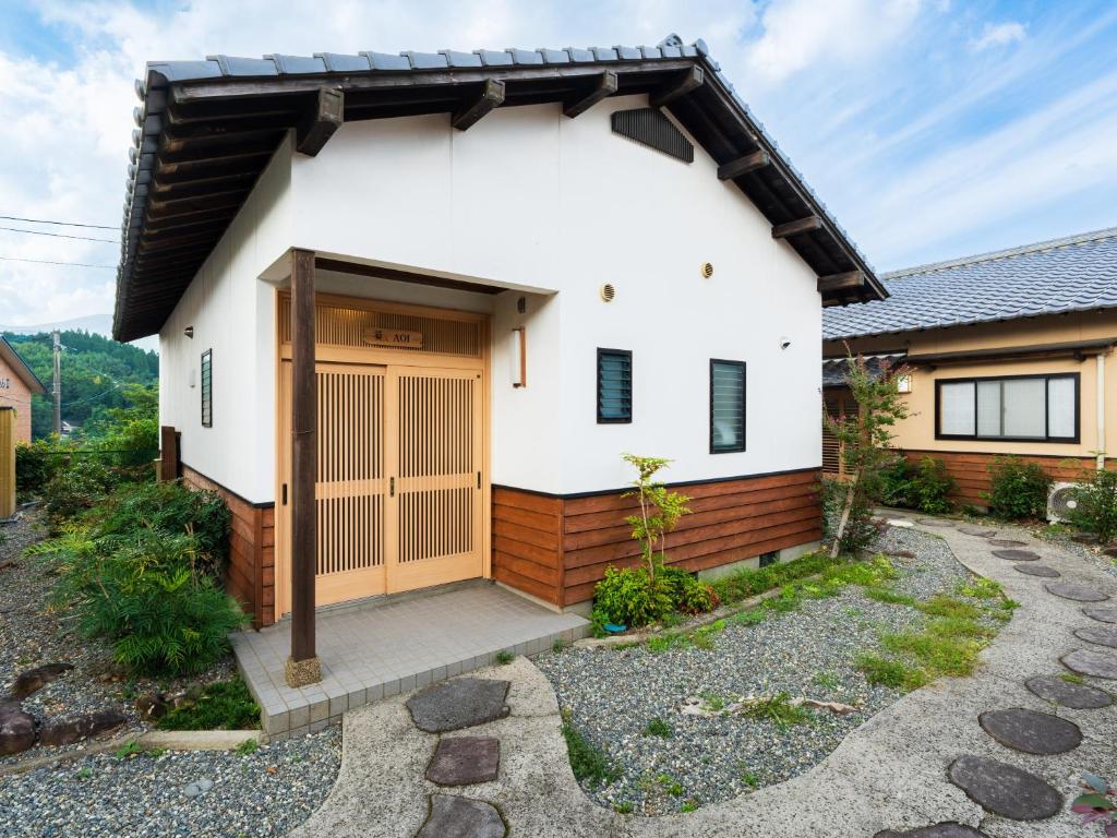une petite maison blanche avec une porte en bois dans l'établissement Yufuin Hanarenoyado Yukagetsu, à Yufu