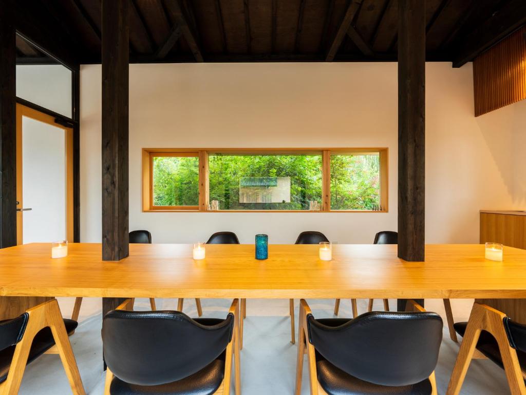 une salle de conférence avec une grande table et des chaises en bois dans l'établissement Yufuin Hanarenoyado Yukagetsu, à Yufu