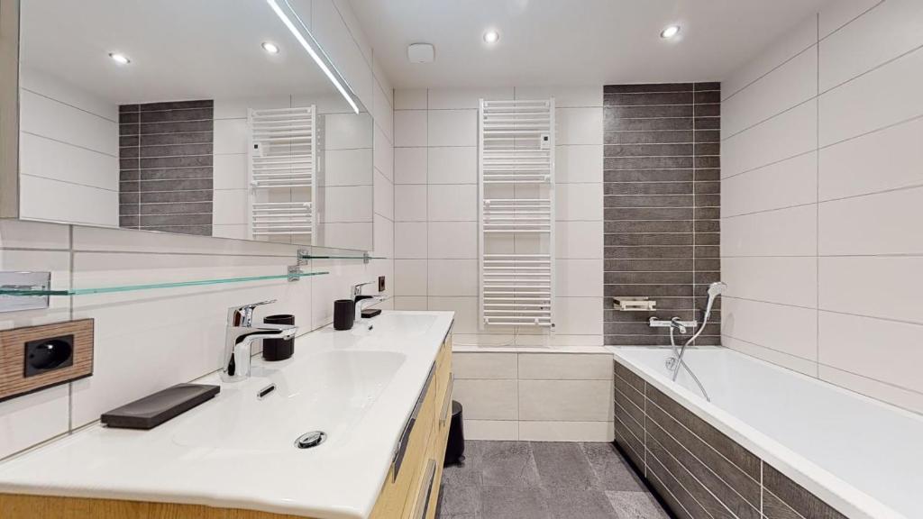 La salle de bains blanche est pourvue d'un lavabo et d'une baignoire. dans l'établissement Résidence Hôtelière Bellecôte 4 étoiles, à La Plagne Tarentaise