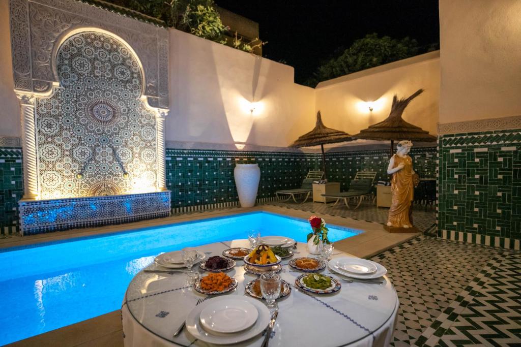 - une table avec des assiettes de nourriture à côté de la piscine dans l'établissement Riad Fes Ziyat & Spa, à Fès