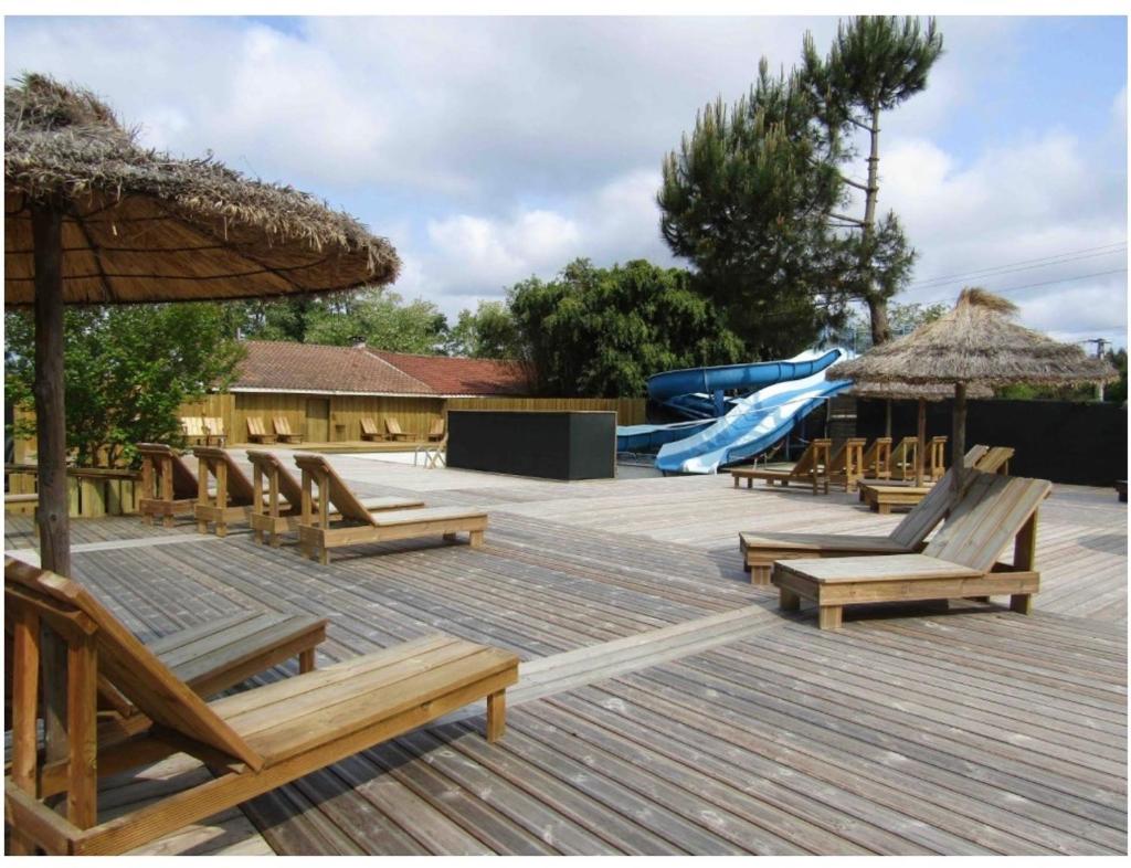 une terrasse avec des chaises et une aire de jeux avec un toboggan dans l'établissement Mammiehome - 6 places - Mimizan - Camping La Lande, à Mimizan