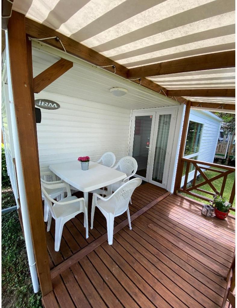 une table et des chaises blanches sur une terrasse en bois dans l'établissement Mobile home proche de EUROPA PARK, à Boofzheim