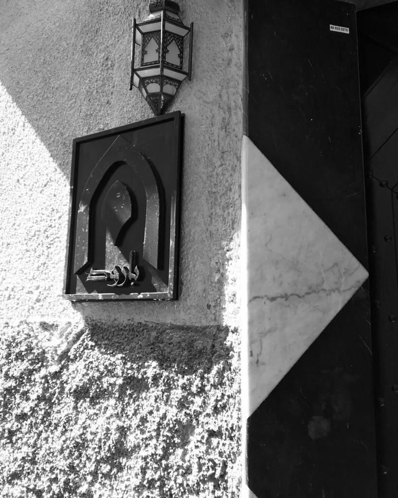 une photo en noir et blanc d'une lumière sur un bâtiment dans l'établissement Riad Baroud, à Marrakech