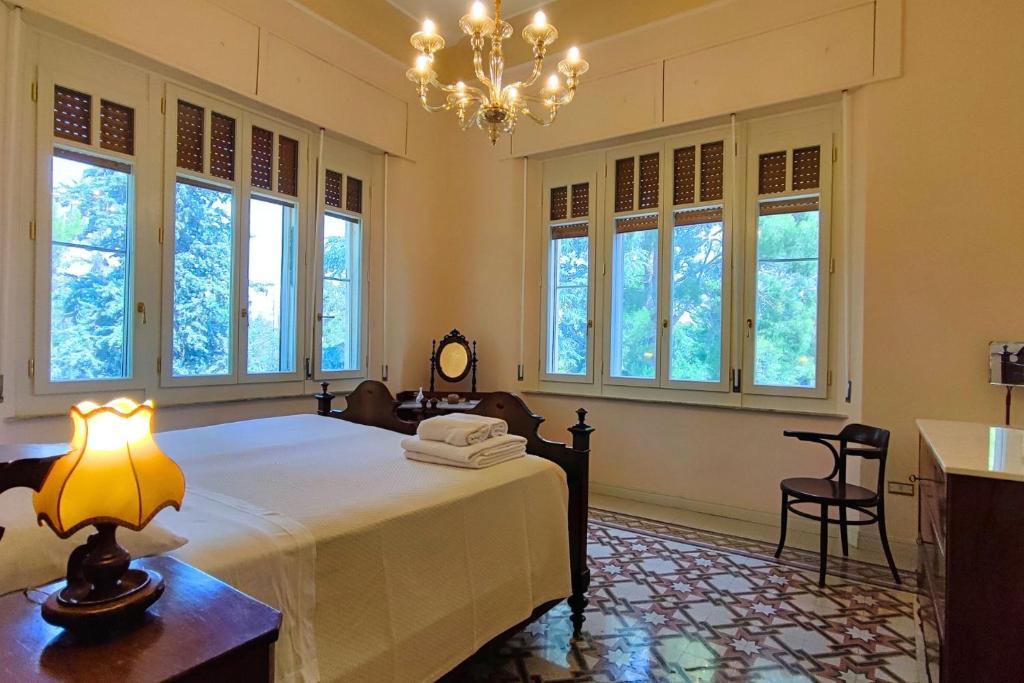 - une chambre avec un lit, un lustre et des fenêtres dans l'établissement Villa Fazi - Liberty Style Villa With Private Pool & Park, à Ortezzano