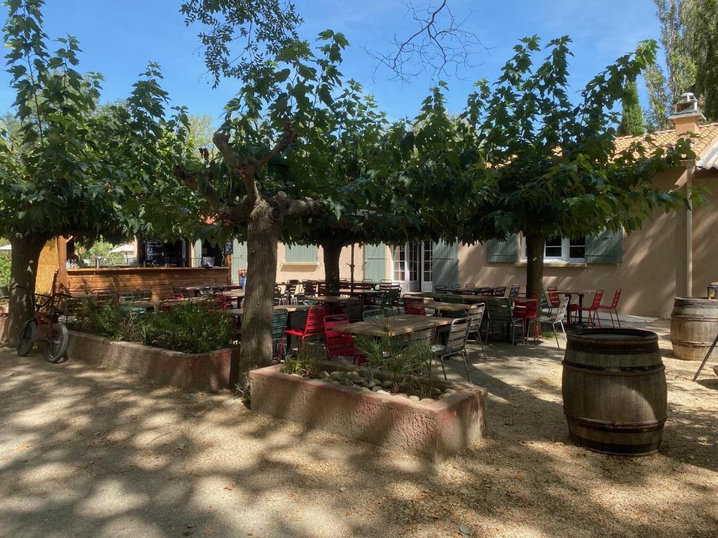 une terrasse avec un arbre, des tables et des chaises dans l'établissement Lodges & Nature - 71, à Avignon 9 autres photos