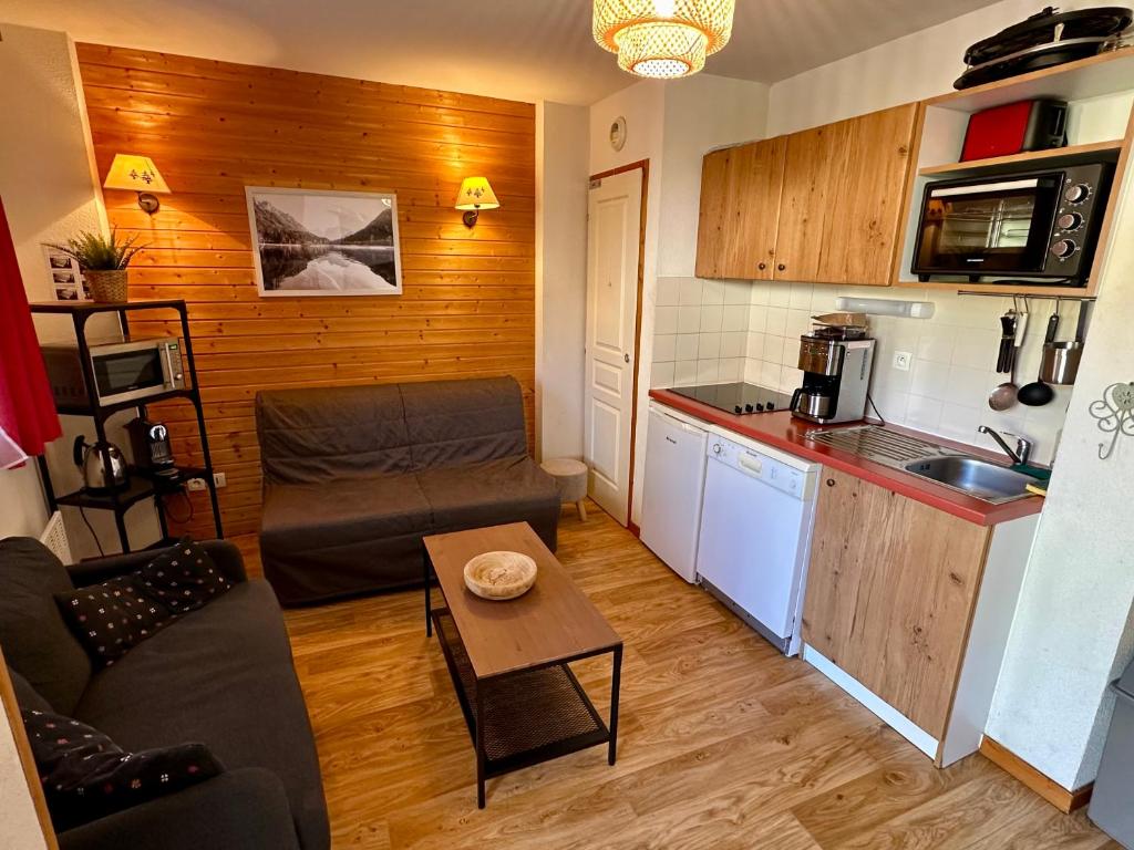 un petit salon avec un canapé et une cuisine dans l'établissement Charmant appartement confortable pour 6 personnes 40m2 pied pistes, Piscine, wifi, parking, à Chamrousse