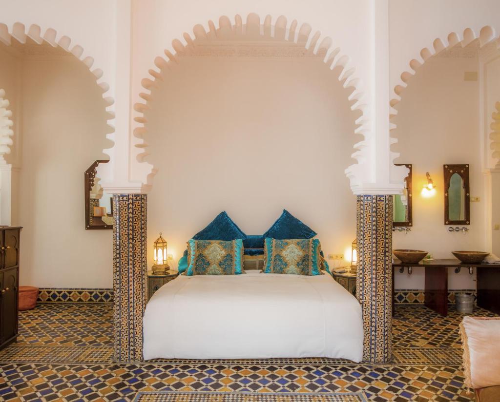 une chambre avec un lit blanc avec des oreillers bleus dans l'établissement Hotel Blanco Riad, à Tetouan