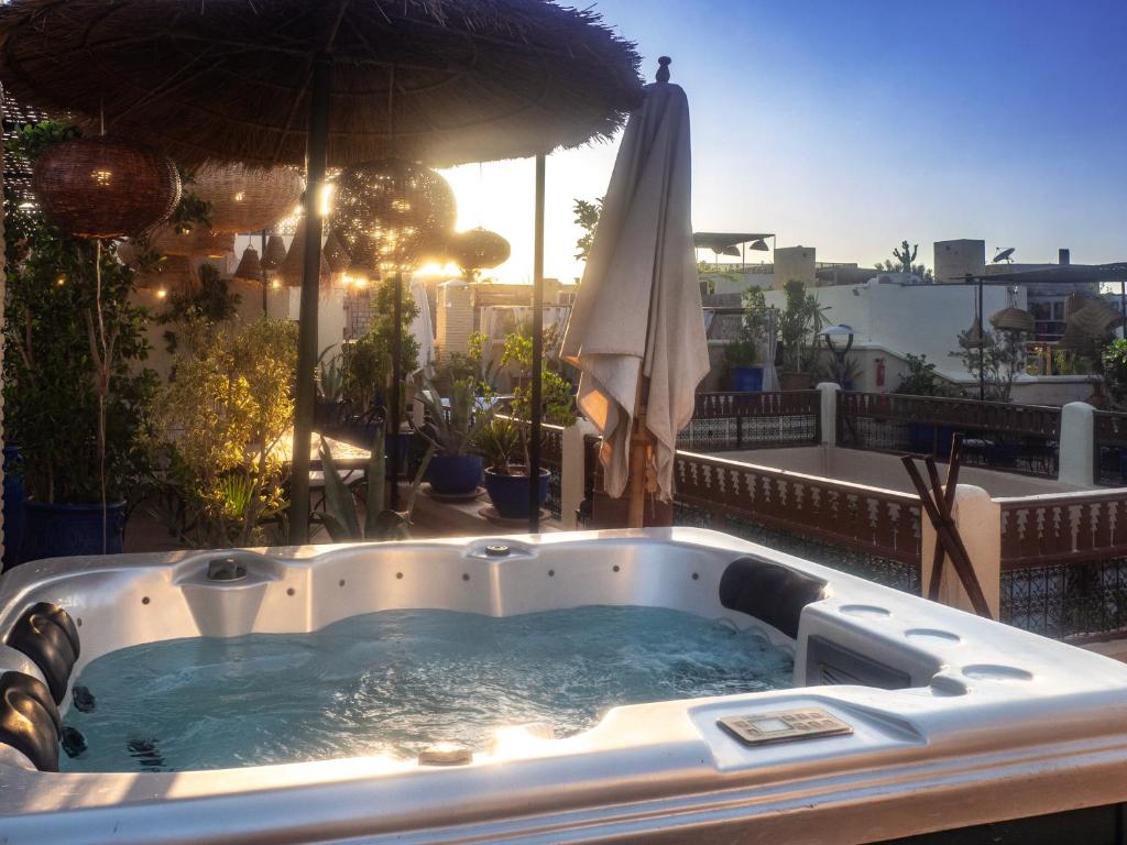 un bain à remous sur un balcon avec un parasol dans l'établissement Riad Dar El Médina - Heated Swimming pool, jacuzzi & Spa, à Marrakech