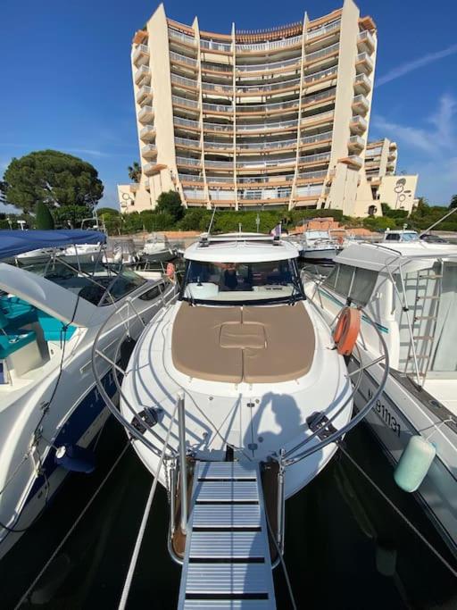 un bateau amarré dans un port de plaisance avec un grand bâtiment dans l'établissement Séjour sur bateau de plaisance, à Mandelieu-la-Napoule