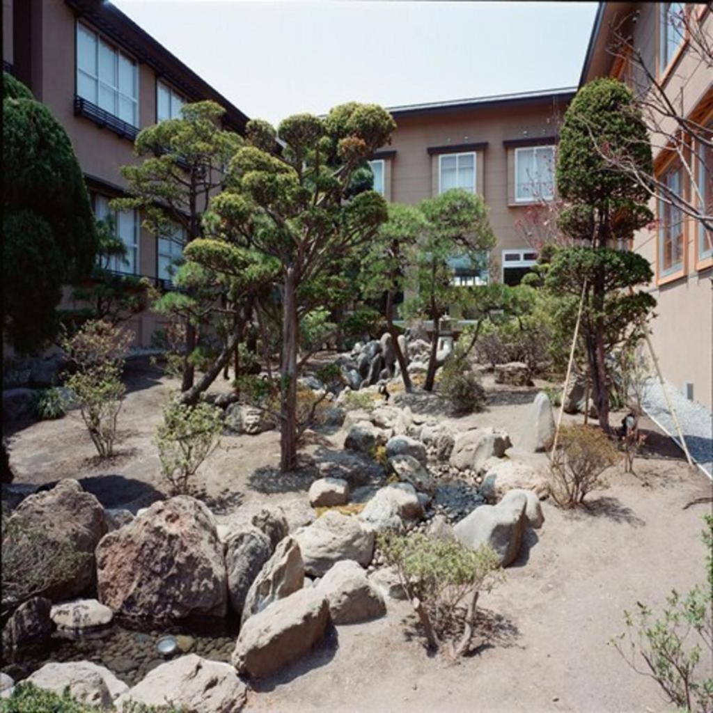 un jardin avec des rochers et des arbres devant un bâtiment dans l'établissement Ryokan Ichinomatsu, à Hakodate 37 autres photos