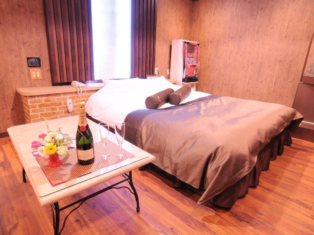 - une chambre avec un lit et une table avec une bouteille de vin dans l'établissement Restay Morioka - Adult Only, à Morioka
