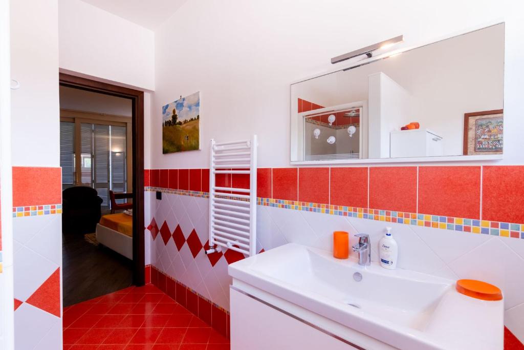 La salle de bains est pourvue d'un lavabo blanc et de carreaux rouges. dans l'établissement Mondello luxury villa con piscina, à Mondello