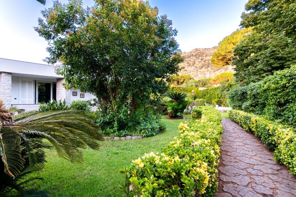 un jardin avec des buissons et un chemin en briques dans l'établissement Mondello luxury villa con piscina, à Mondello