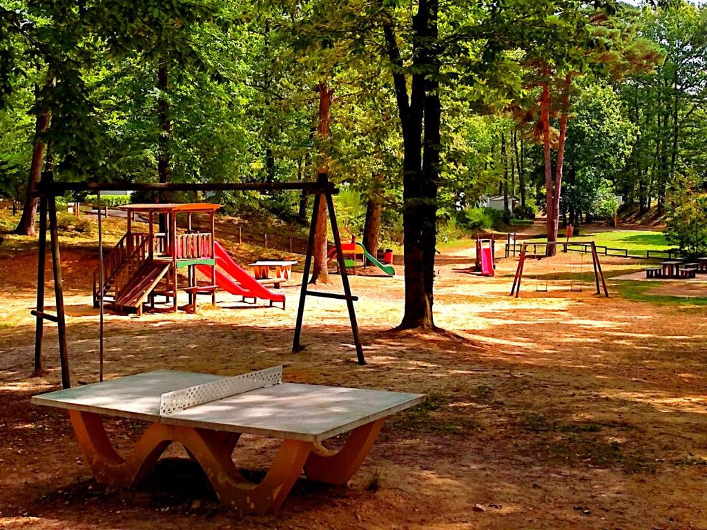 un parc avec une aire de jeux avec un banc et des balançoires dans l'établissement Mobil Home près de l'entrée et de la piscine, à Saint-Chéron