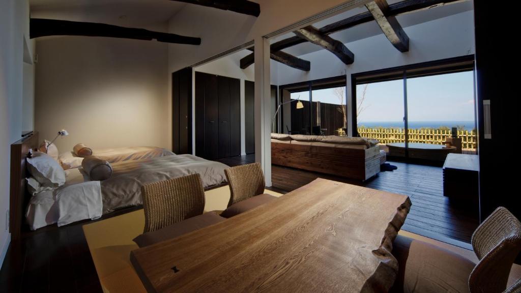une chambre avec un lit et une table et une grande fenêtre dans l'établissement Fugaku Gunjo, à Izu