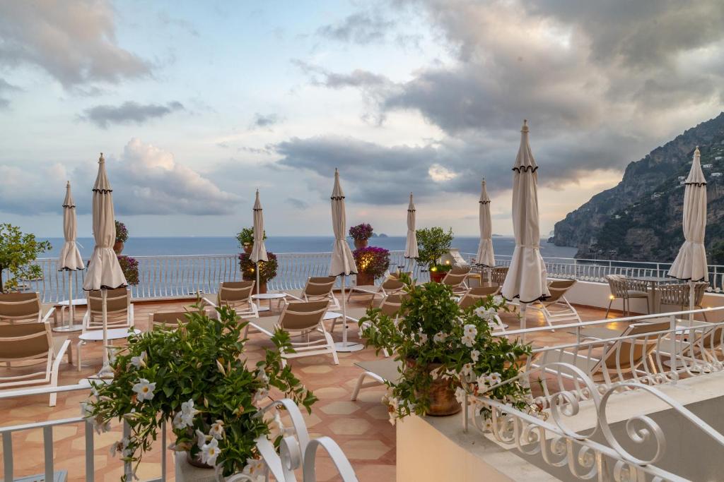 un groupe de chaises et de parasols sur une terrasse dans l'établissement Hotel Marincanto, à Positano