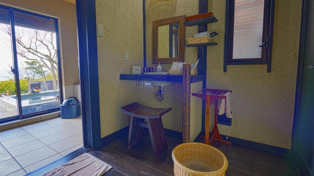 La salle de bains est pourvue d'un lavabo, d'un tabouret et d'un miroir. dans l'établissement 森の入り江の離れ宿 無雙庵枇杷, à Toi