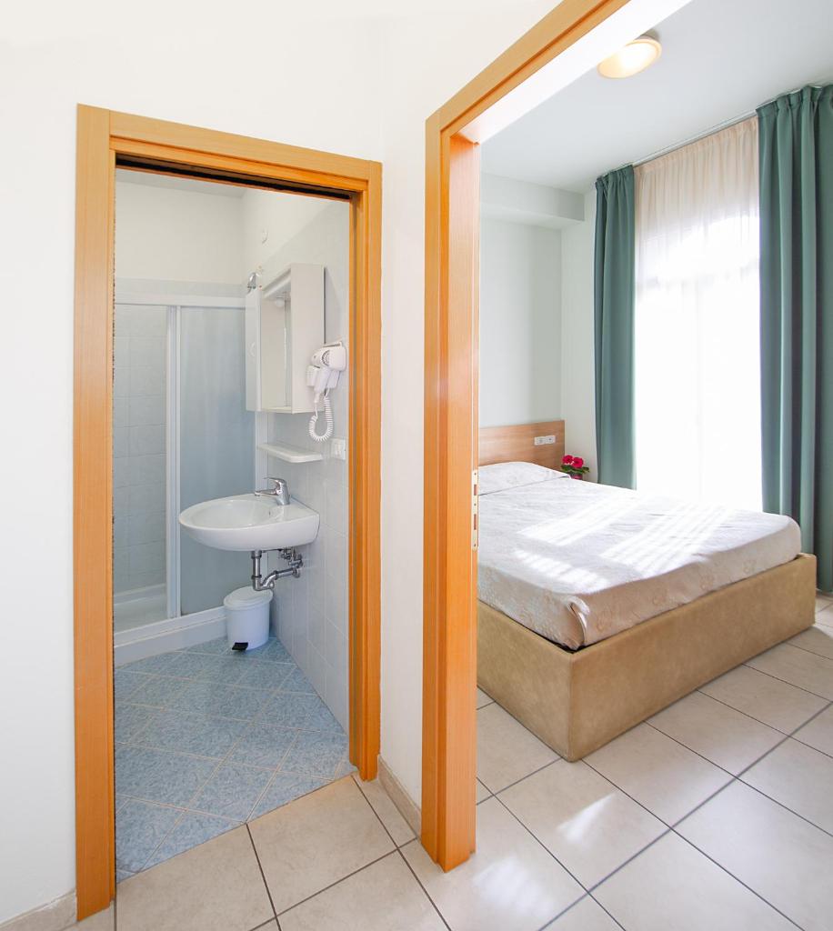 une chambre avec un lit, un lavabo et un miroir dans l'établissement Hotel Ginevra, à Lido di Jesolo