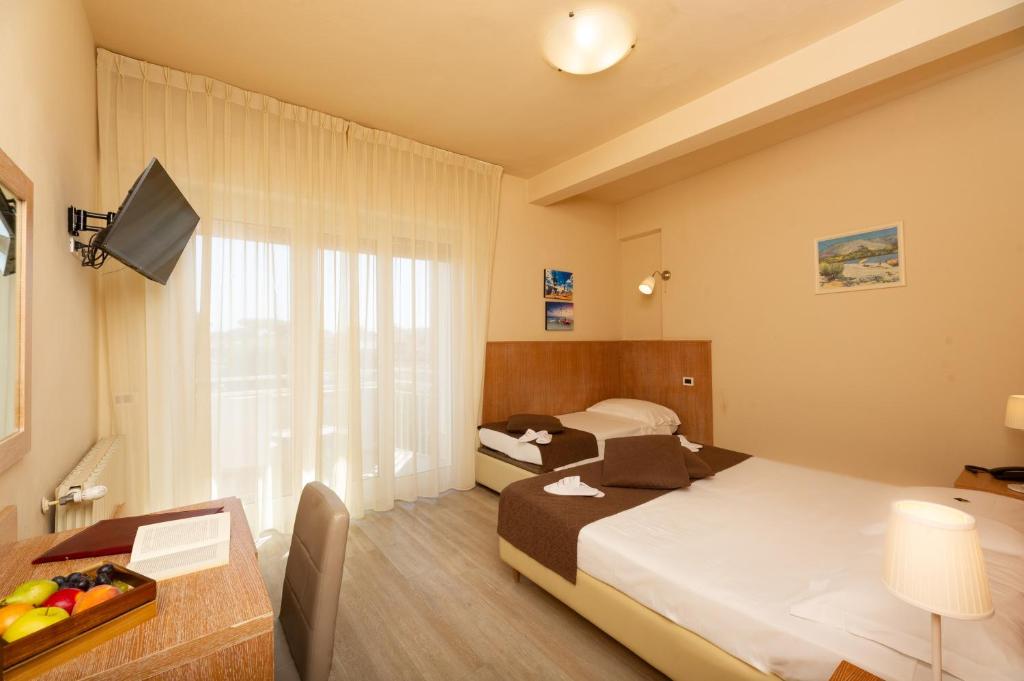 une chambre d'hôtel avec deux lits et un bureau avec une télévision dans l'établissement Hotel Nuova Sabrina, à Marina di Pietrasanta 42 autres photos
