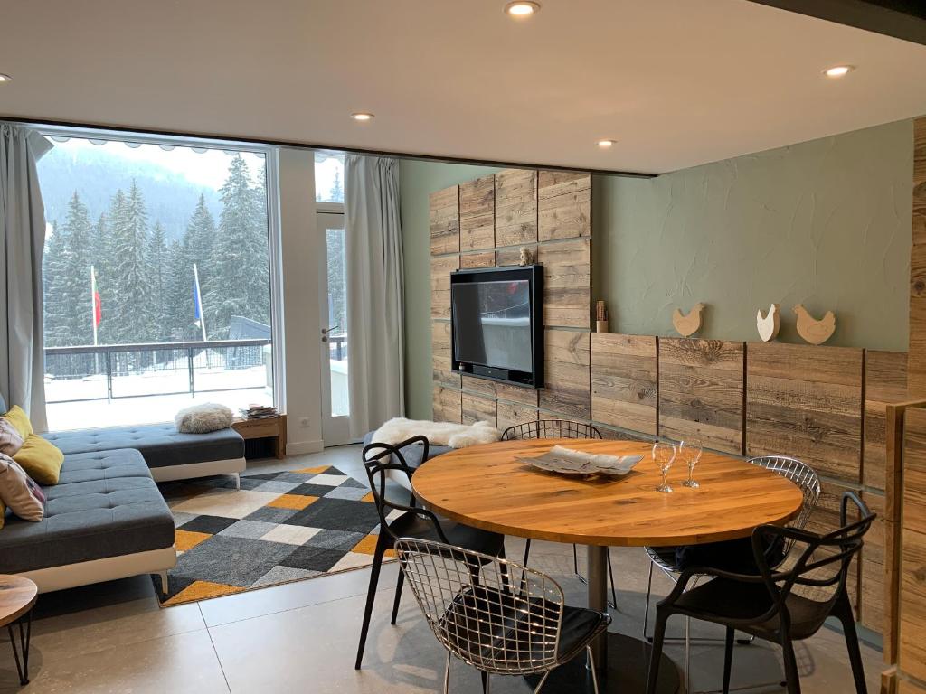 - un salon avec une table en bois et une télévision dans l'établissement Flaine Forum H1 Cassiopée Mezzanine & Terrasse, à Flaine