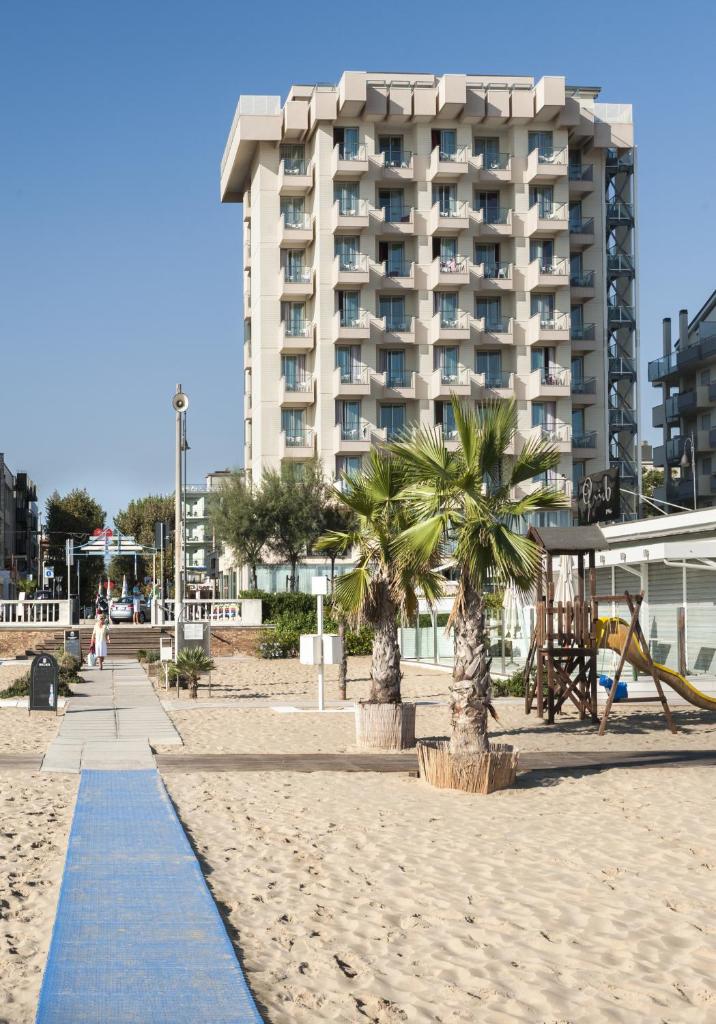 un hôtel sur la plage avec des palmiers et un trottoir dans l'établissement Terminal Palace & SPA, à Rimini