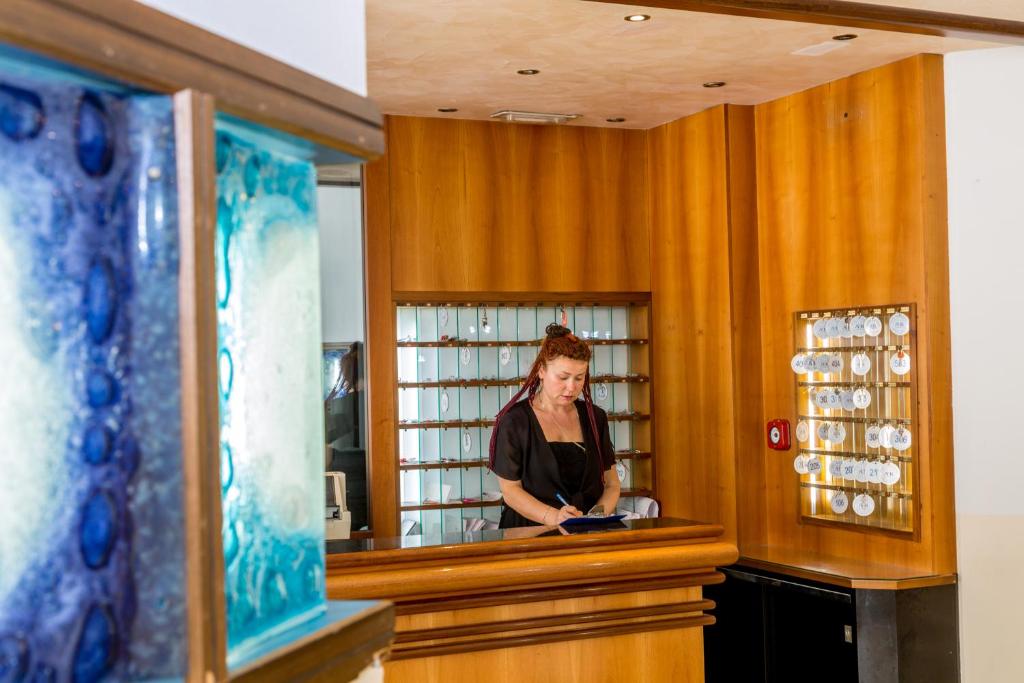 une femme debout derrière un comptoir dans une pièce dans l'établissement Hotel Alla Rotonda, à Lido di Jesolo 33 autres photos