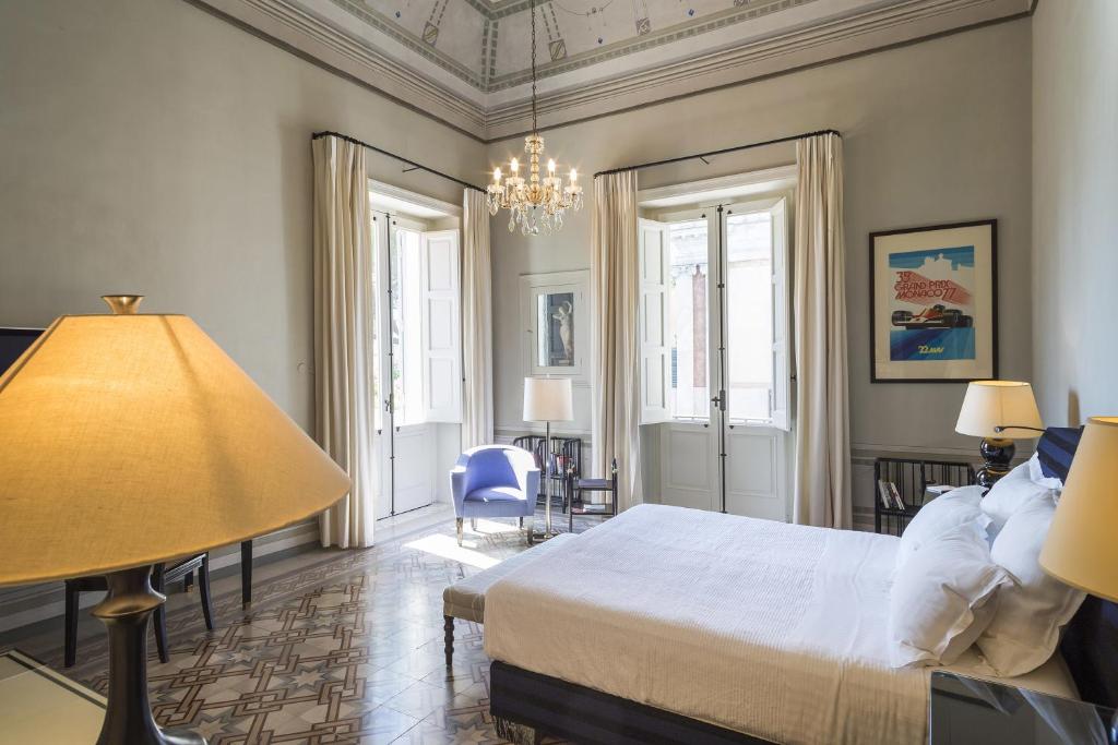 une chambre avec un grand lit et un lustre dans l'établissement Palazzo Margherita, à Bernalda