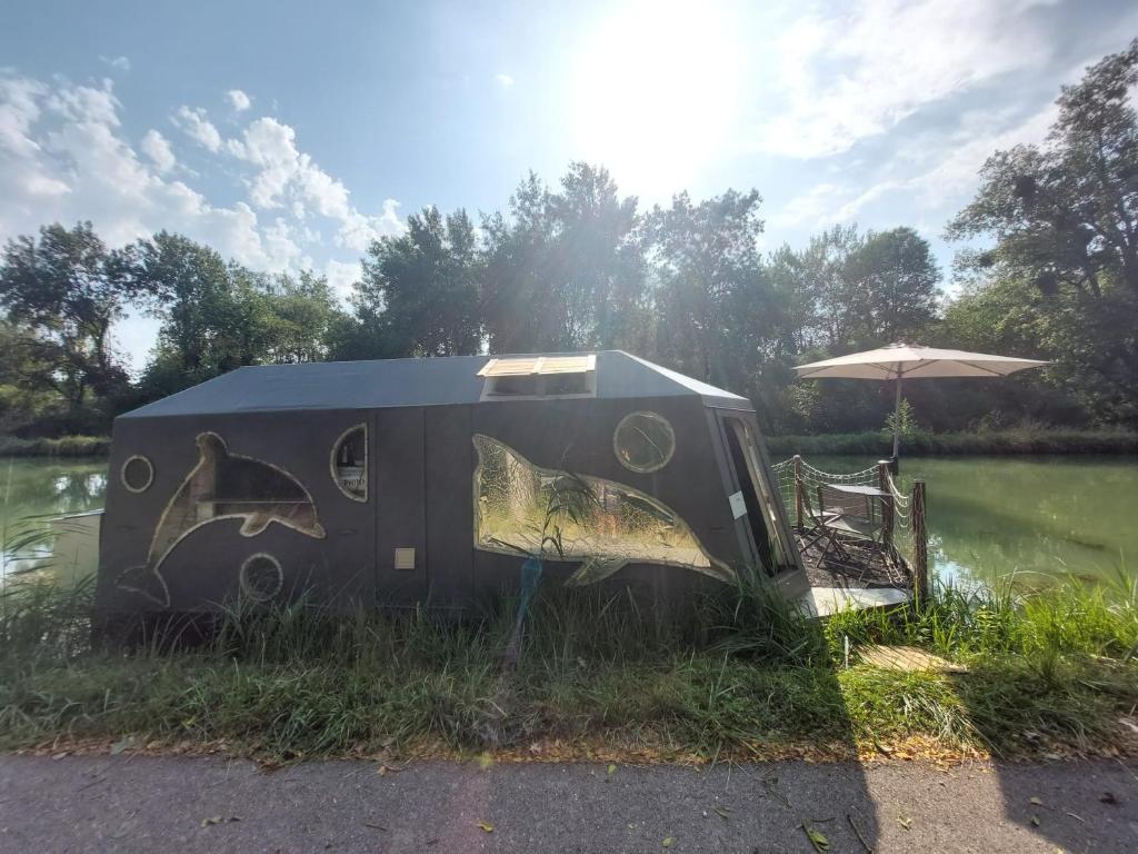 Une remorque avec un tableau assise à côté d'un lac dans l'établissement Bateau studio terrasse vue sur l'eau et nature, à Saint-Usage