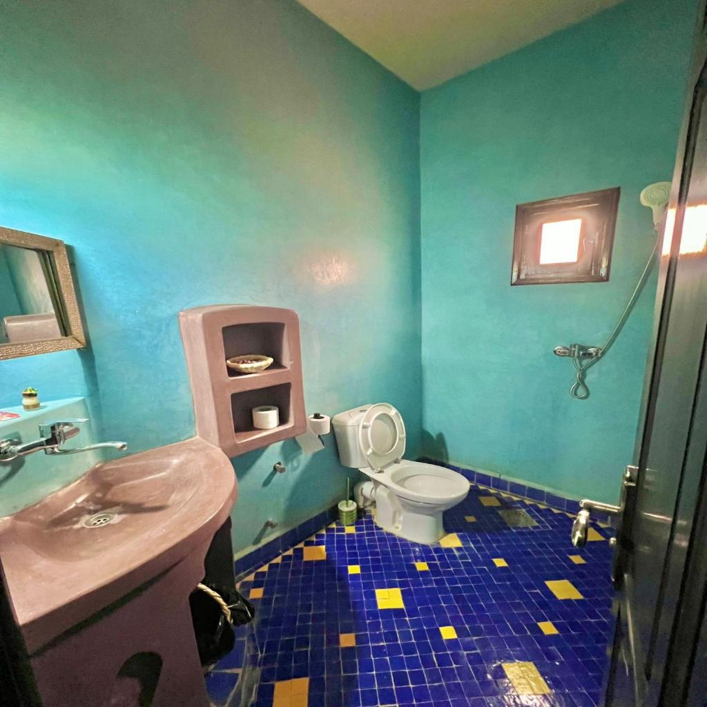une salle de bain bleue avec des toilettes et un lavabo dans l'établissement Riad Hassi Labied Merzouga, à Merzouga