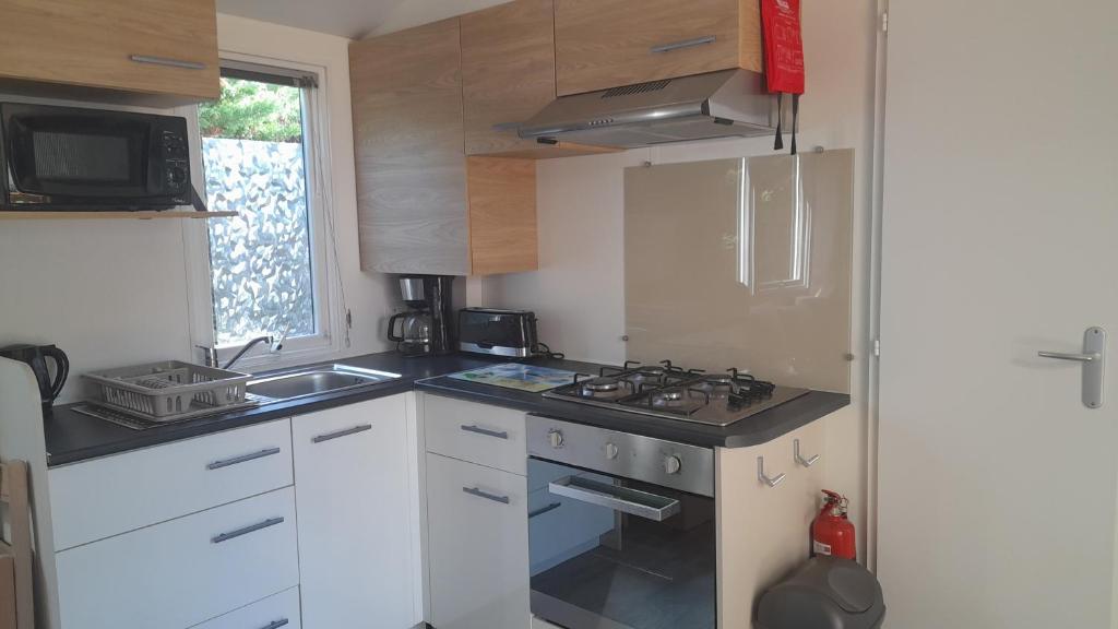 Il comprend une petite cuisine équipée d'une cuisinière et d'un évier. dans l'établissement MOBILHOME EN BORD DE MER sur camping 4 étoiles, à Saint-Jean-de-Monts 3 autres photos