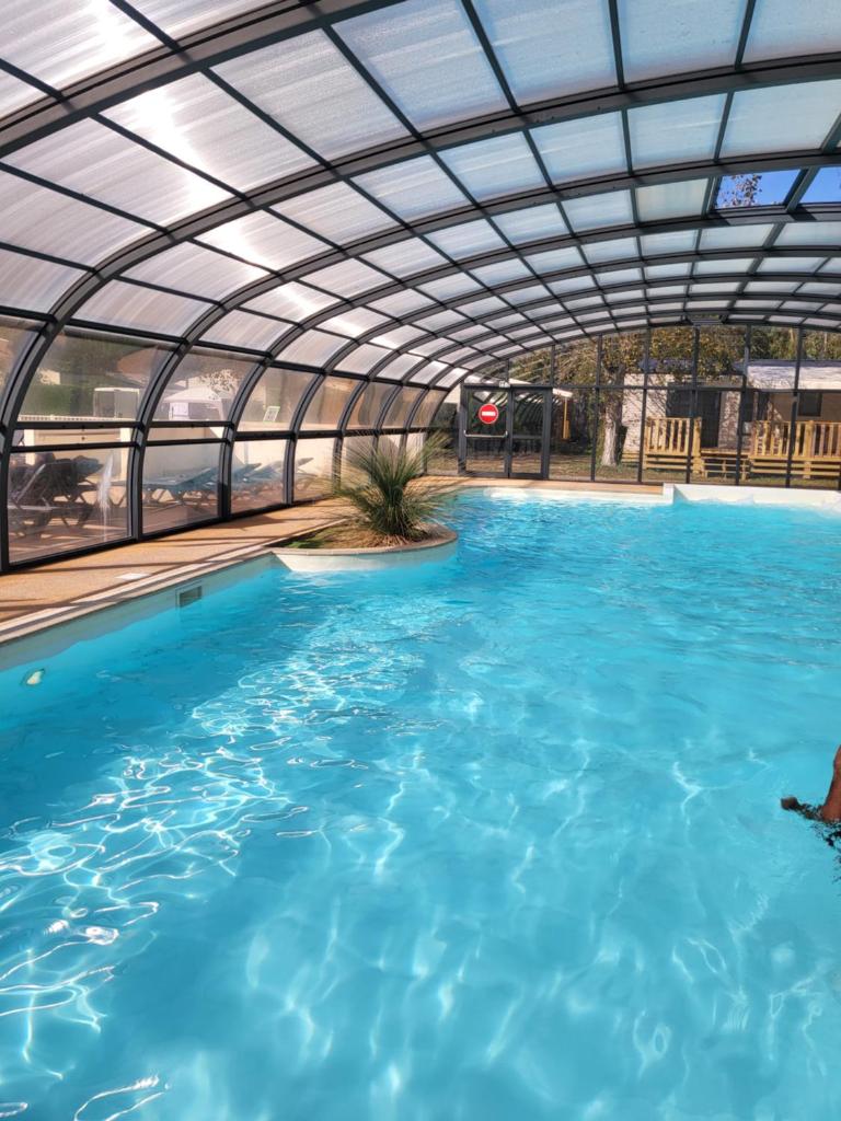 une grande piscine avec un toit rétractable dans l'établissement "Les pieds dans l'Orne" - Mobil home 5 personnes, à Ouistreham