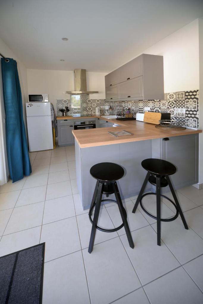 une cuisine avec deux tabourets de bar et un comptoir dans l'établissement Gîte D&D avec piscine privative, à Martel