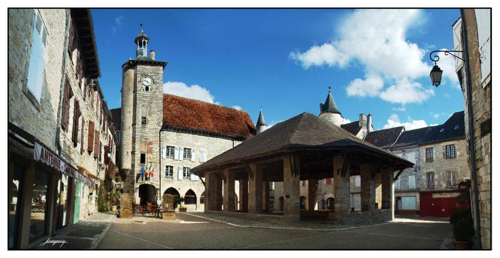 un vieux bâtiment avec une tour d'horloge dans une rue dans l'établissement Gîte D&D avec piscine privative, à Martel