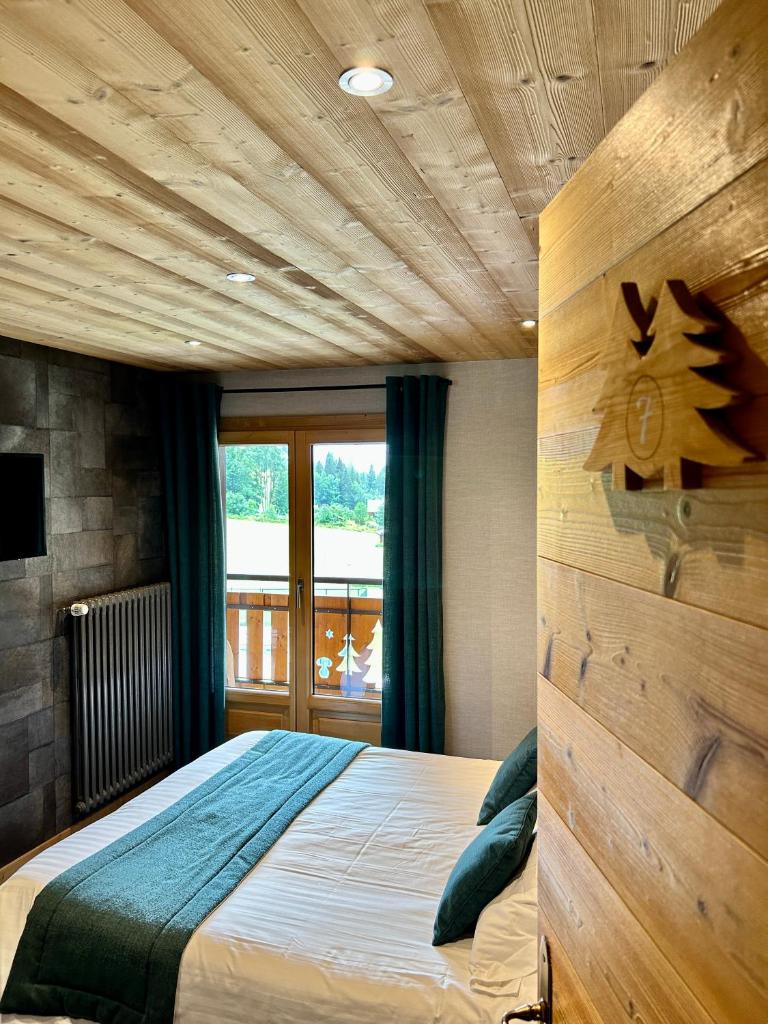 une chambre avec un grand lit avec un plafond en bois dans l'établissement Hameau des Prodains - Hôtel, à Morzine 37 autres photos